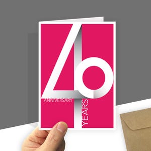 Pode incluir: Um cartão de felicitações retangular com um fundo magenta vibrante apresentando um grande número 40 branco estilizado. O texto "ANNIVERSARY" está impresso em letras brancas pequenas abaixo do número, e "YEARS" está impresso verticalmente em branco.