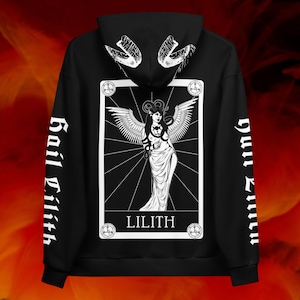 May include: Black hoodie featuring a white graphic of Lilith, a winged figure, on the back. The design includes the word "LILITH" and the phrase "Hail Lilith" on the sleeves. The hood has a white snake design.