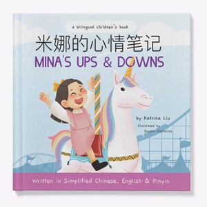 May include: A book cover with a colorful illustration of a girl riding a carousel unicorn. The title of the book is "Mina's Ups & Downs" and is written in both English and Chinese. The book is described as a bilingual children's book.