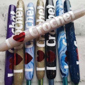 May include: Set of seven crochet hooks with colorful handles and a heart design. Each hook has the word "crochet" written on it in white letters.