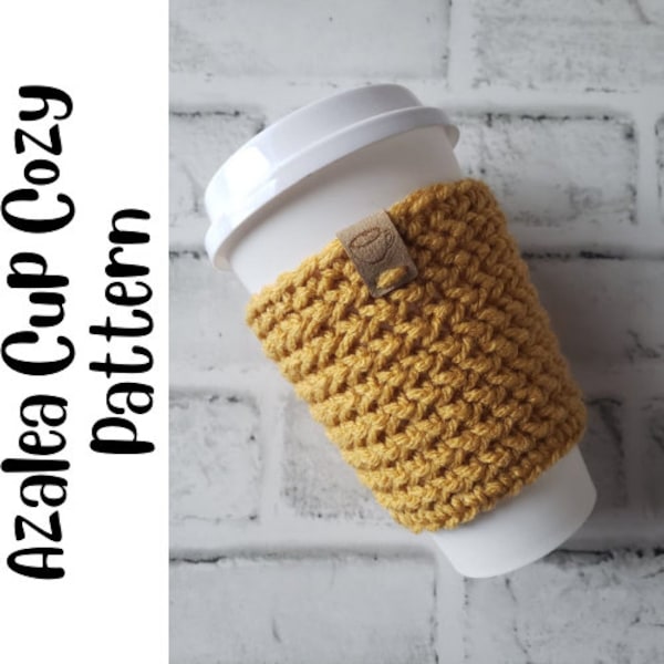 May include: A crocheted cup cozy in a mustard yellow color with a brown leather tag. The cozy is on a white to-go cup.