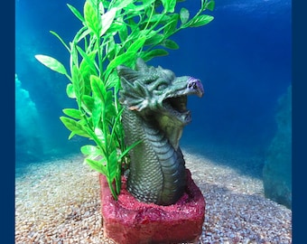 Dragon Head Aquarium Decoration.  Red base, green-purple dragon head and very tall green plants. Fantasy fish tank ornament.