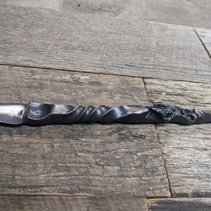 May include: A black metal bottle opener with a twisted handle and a dragon head design.