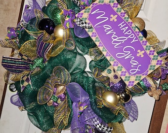 May include: A green, gold, and purple Mardi Gras wreath with a sign that reads "Happy Mardi Gras".