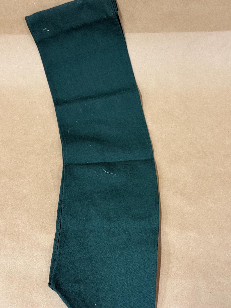 May include: Dark green denim pants folded neatly. The pants are a solid color and appear to be made of a durable fabric. The image shows the pants from the waist to the knees.