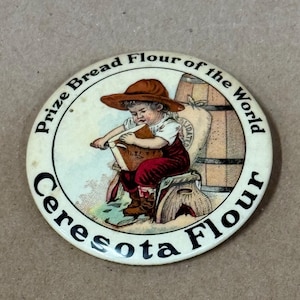 May include: A vintage round button with the text "Prize Bread Flour of the World" and "Ceresota Flour". The button features a child in a hat, seated and holding a book, with a flour sack and barrel in the background.
