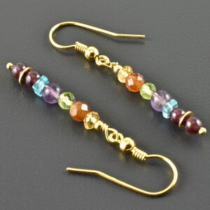 Könnte beinhalten: Goldene Ohrhänger mit einer Reihe bunter Edelsteinperlen, darunter Granat, Amethyst, Peridot, Citrin und Topas.