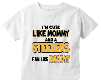 May include: White t-shirt with black and yellow text that reads "I'm cute like mommy and a Steelers fan like daddy!"