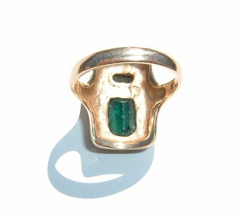 May include: A gold ring with a green emerald gemstone set in a rectangular shape.