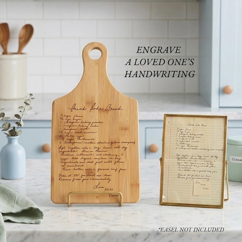 May include: A light-colored wooden cutting board with a handle and a hole, featuring an engraved recipe titled Irish Soda Bread. Next to it is a framed handwritten recipe on lined paper. Text on the image reads: ENGRAVE A LOVED ONE'S HANDWRITING.