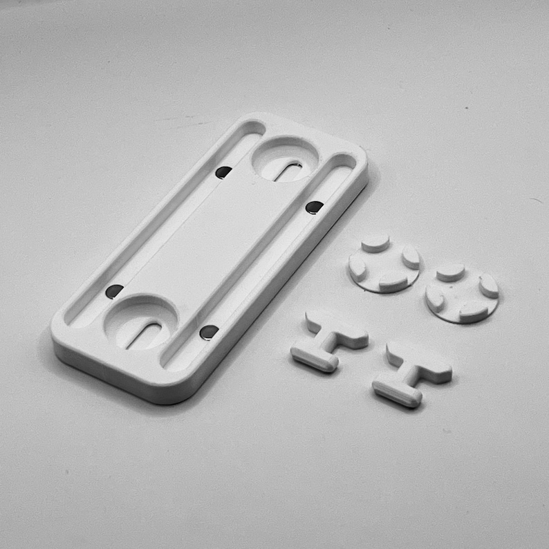 Peut inclure: Un composant rectangulaire blanc avec deux d&eacute;coupes circulaires et plusieurs petits trous. Il y a aussi deux petites pi&egrave;ces rondes multilob&eacute;es et deux pi&egrave;ces en forme de T. Tous les articles sont en mat&eacute;riau opaque.