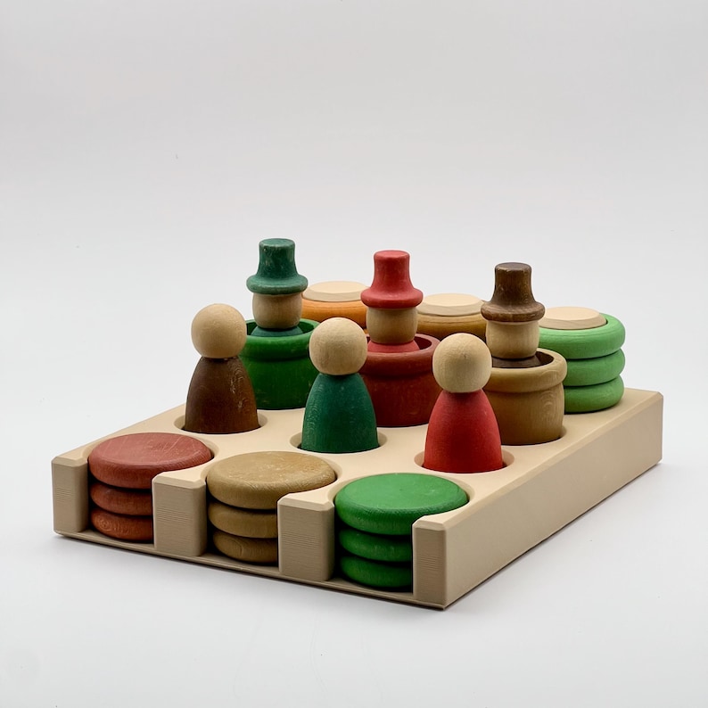 May include: A wooden toy set with colorful stacking figures and circles. The figures have different colored hats and bodies. The circles are stacked in different colors and sizes. The set is arranged on a wooden tray.