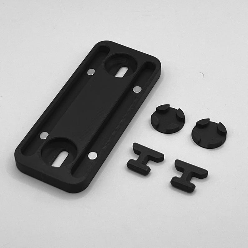 Peut inclure: Une plaque de montage rectangulaire noire avec deux trous circulaires et quatre petits aimants argent&eacute;s. Deux pi&egrave;ces noires circulaires et deux pi&egrave;ces noires en forme de T sont &eacute;galement incluses.