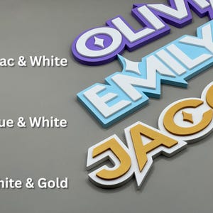 May include: Three-dimensional name signs in lilac and white, blue and white, and white and gold. The names "Olivia", "Emily", and "Jacob" are displayed in a layered design. The text "Lilac & White", "Blue & White", and "White & Gold" are also visible.