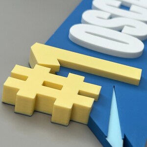 May include: A blue sign with white text and yellow accents. The sign features the word "ALSO" in white, a yellow number one, and a yellow hashtag symbol. The sign is angled, with a grey background.