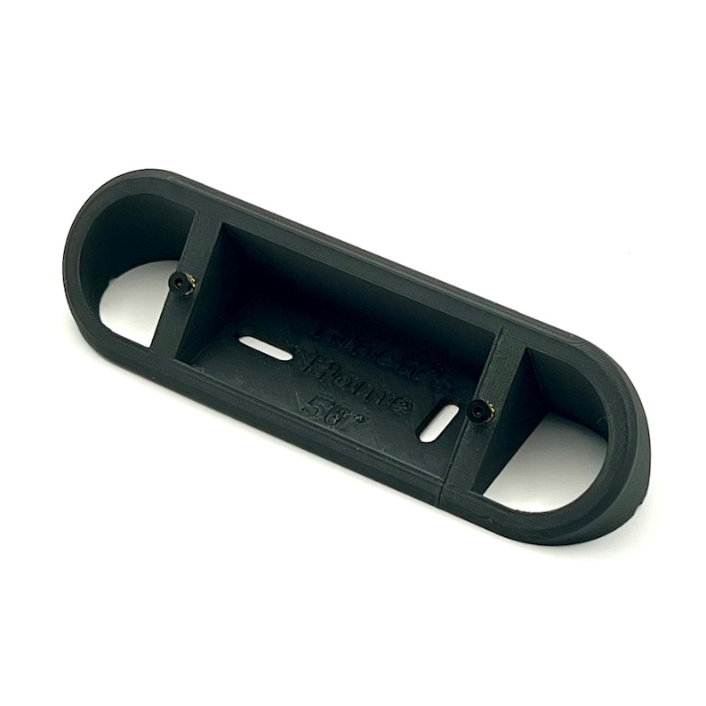 May include: Black plastic 3D printed part with the text "Miniature" and "56r" printed on it. The part has two holes and a slot.