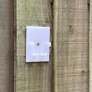 May include: White plastic wall mount with four small rectangular slots and a single screw hole in the center.