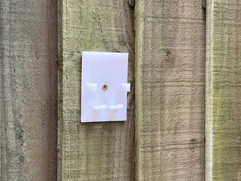May include: White plastic wall mount with four small rectangular slots and a single screw hole in the center.