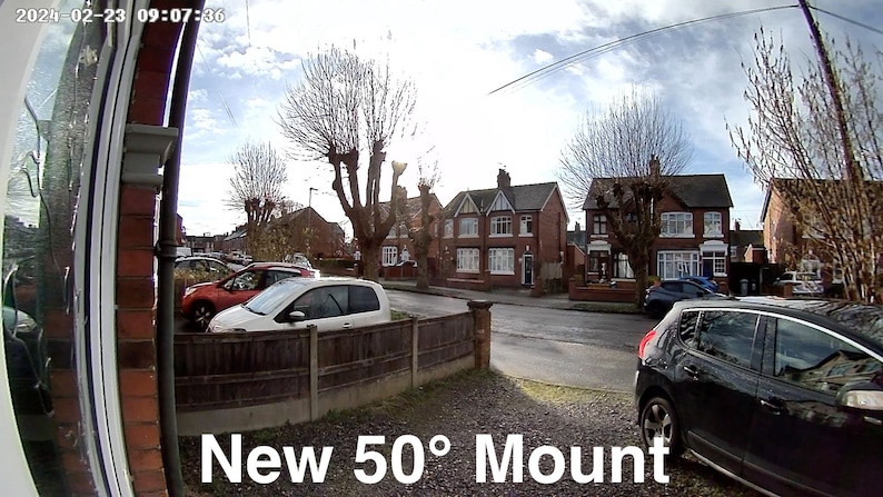 May include: A wide-angle view of a residential street with houses and trees. A black car is parked in the driveway, and a white car is parked in the street. The text "New 50&deg; Mount" is visible in the lower right corner of the image.