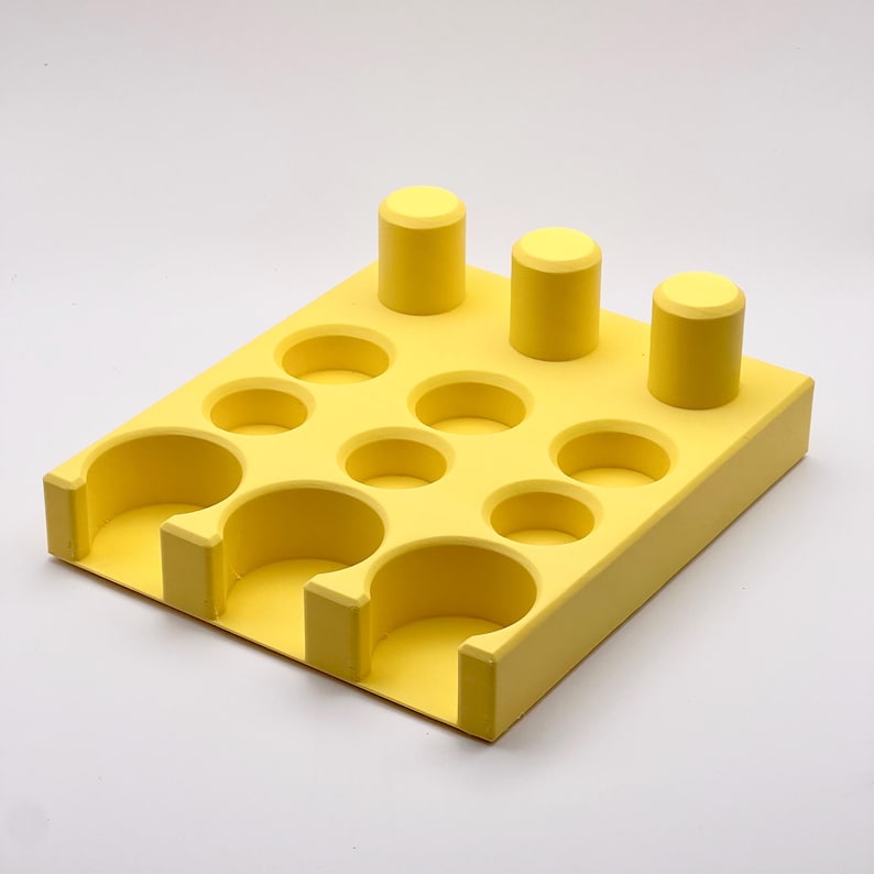 May include: Yellow plastic organizer with multiple round and rectangular compartments. The organizer has three vertical columns with round tops.