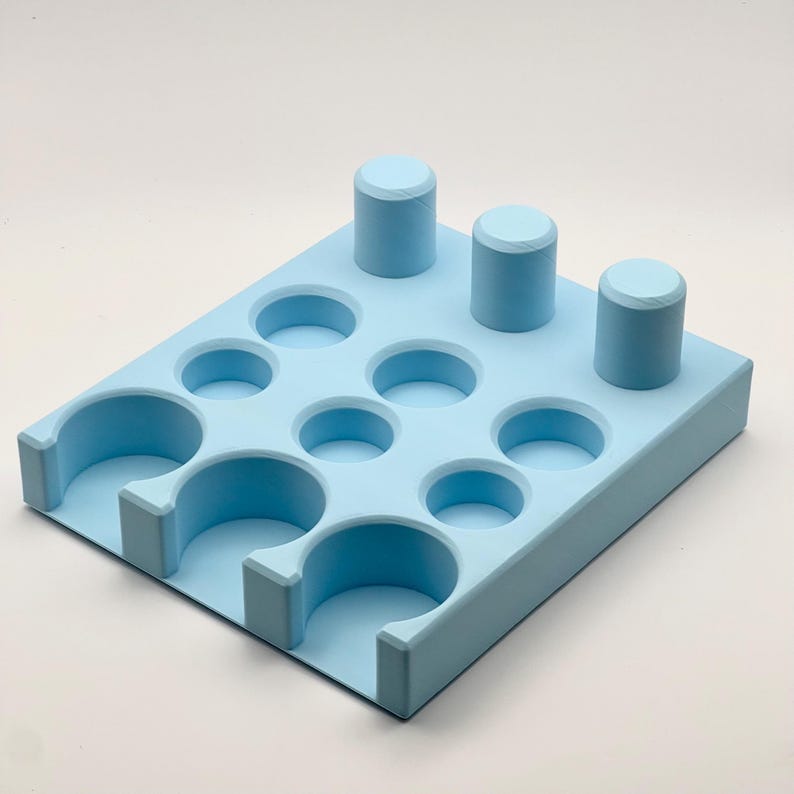 May include: A light blue plastic organizer with 10 round compartments and 3 vertical slots. The organizer is designed to hold small items like bottles or tubes.
