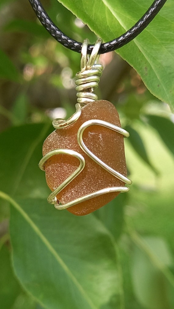 Brown Wire Wrapped Sea Glass Necklace designed using an 18-gauge silver tarnish-resistant wire with 20” length black waxed cotton cord.
