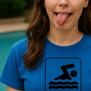 May include: A blue t-shirt with a black swimming sign and the text "Hey! Over here. I've found bacon!!" The person wearing the shirt is making a silly face with their tongue out and eyes crossed.
