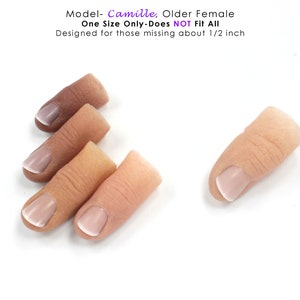 May include: Four silicone fingertip prosthetics with a natural skin tone and white nail polish. The fingertip prosthetics are arranged in a row, with the fingertip on the right slightly angled. The text "Model- Camille, Older Female One Size Only-Does NOT Fit All Designed for those missing about 1/2 inch" is visible at the top of the image.