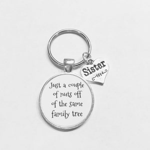 May include: Silver keychain with a round charm that reads "Just a couple of nuts off of the same family tree". A smaller heart-shaped charm with the word "Sister" is attached to the keychain.