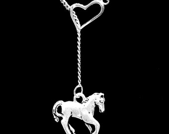 May include: A silver necklace with a heart charm and a horse pendant. The necklace is on a black background.