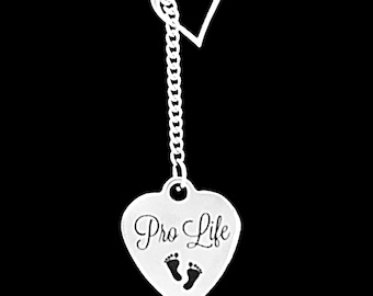 May include: Silver-toned necklace with a heart-shaped pendant. The pendant has the words "Pro Life" and two small footprints. The necklace features a chain with a second open heart design near the top.