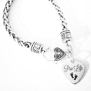 May include: Silver bracelet with a heart charm that says "Pro Life" with a footprint design.