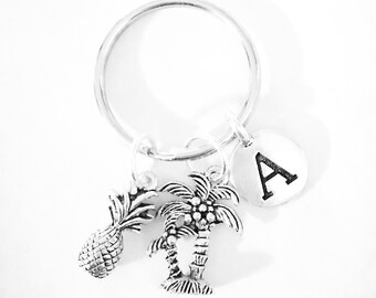 May include: Silver keyring with a pineapple, palm tree, and a round charm with the letter A.