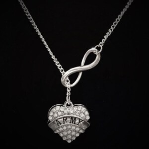 Peut inclure: Collier en argent avec un symbole d'infini et un pendentif en forme de c&oelig;ur. Le pendentif en forme de c&oelig;ur est incrust&eacute; de strass et porte l'inscription "ARMY".