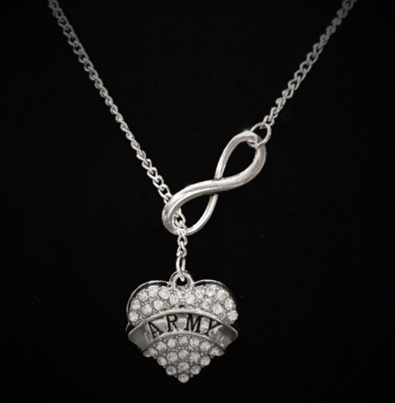 Peut inclure: Collier en argent avec un symbole d'infini et un pendentif en forme de c&oelig;ur. Le pendentif en forme de c&oelig;ur est incrust&eacute; de strass et porte l'inscription "ARMY".