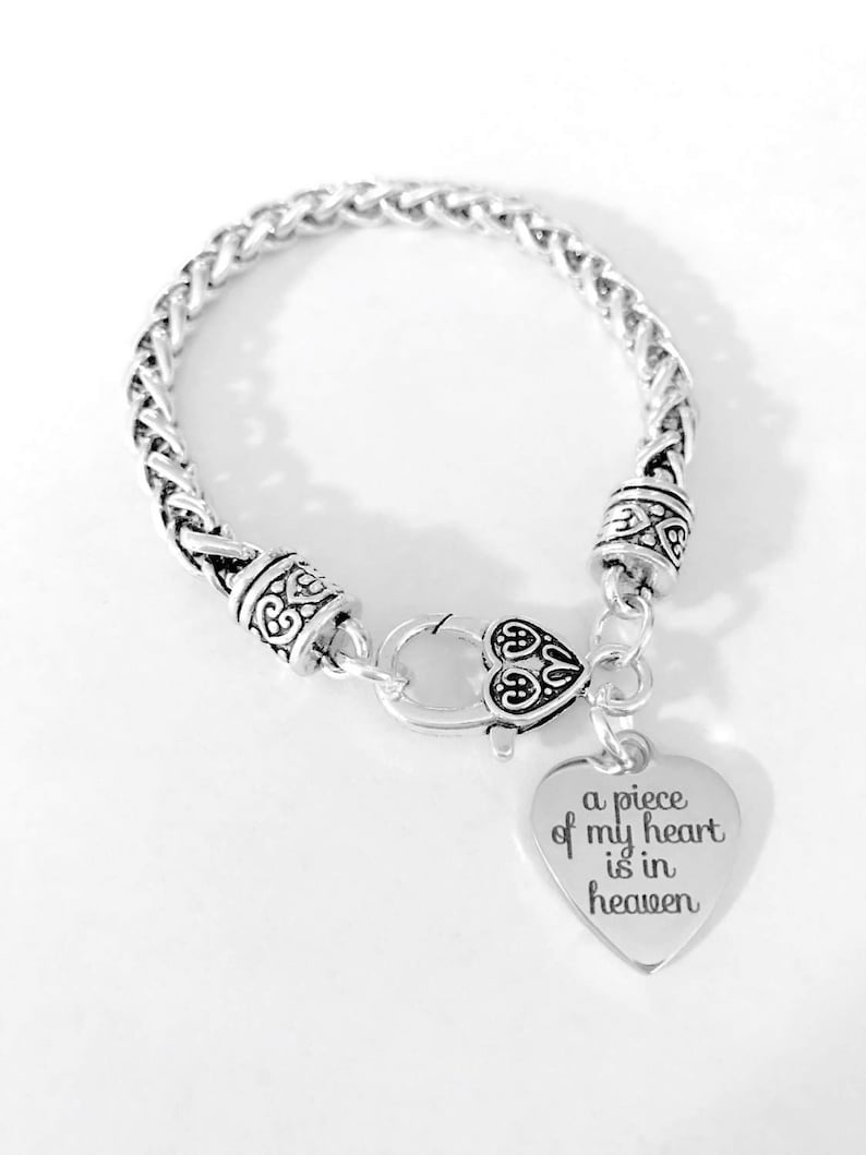 Op de afbeelding: Zilveren armband met een hartvormige bedel met de tekst "a piece of my heart is in heaven".