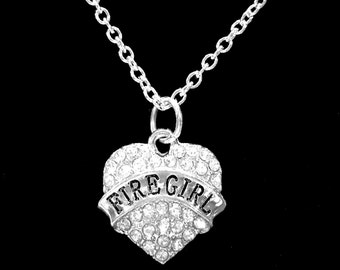 May include: Silver necklace with a heart-shaped pendant that has clear rhinestones and the word "FIRE GIRL" in black lettering.