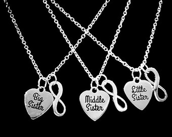 May include: Three silver necklaces with heart-shaped pendants. The pendants say "Big Sister", "Middle Sister", and "Little Sister". Each pendant is attached to an infinity symbol.