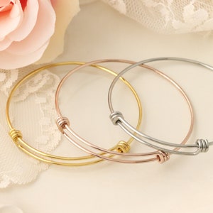 May include: Three expandable bangle bracelets in gold, rose gold, and silver.