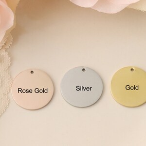 May include: Three round metal discs with different finishes: rose gold, silver, and gold. Each disc has a hole at the top and the finish is labeled in black text.