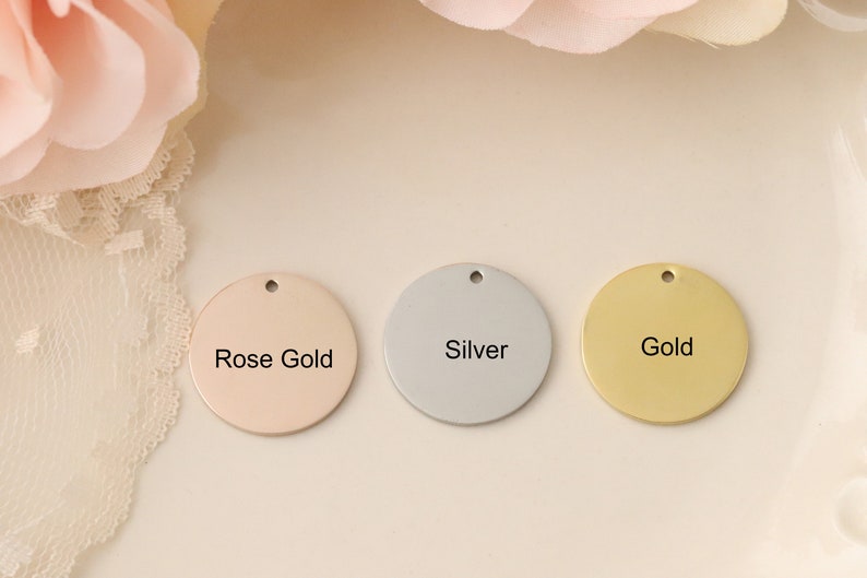 May include: Three round metal discs with different finishes: rose gold, silver, and gold. Each disc has a hole at the top and the finish is labeled in black text.