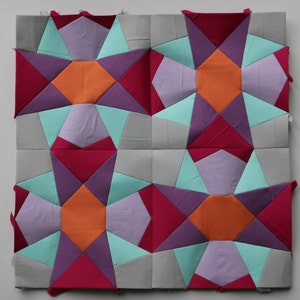 Könnte beinhalten: Vier Stoffquadrate, die zusammengenäht wurden, um einen Quiltblock mit einem Sternmuster zu bilden. Der Block besteht aus vier verschiedenen Farben: Grau, Lila, Orange und Rosa.
