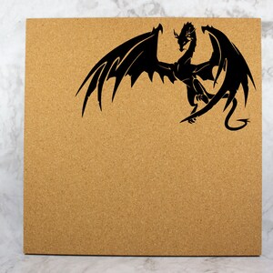 May include: A corkboard with a black silhouette of a dragon with wings spread out.
