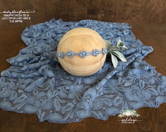 May include: A light blue lace fabric with a wooden ball on top. The ball has a light blue flower headband with silver accents.