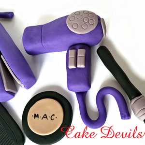 May include: Purple hair dryer, curling iron, makeup brush, and a compact with the text "M.A.C." on the lid. These are all fondant decorations for a cake.