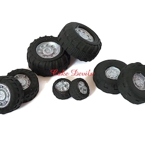 May include: Eight black rubber tire cake toppers with silver rims. The tires are different sizes and are arranged in a cluster.