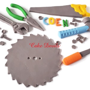 May include: A set of gray, blue, orange, and green toy tools, including a saw, hammer, screwdriver, wrench, pliers, and screws. The tools are arranged on a white background. The word "COEN" is spelled out in colorful letters.