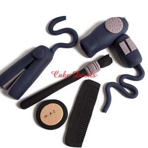 May include: A set of blue and black hair styling tools, including a hairdryer, curling iron, comb, and makeup brush. The makeup brush has a purple handle and the makeup compact has the text "M.A.C." on it.