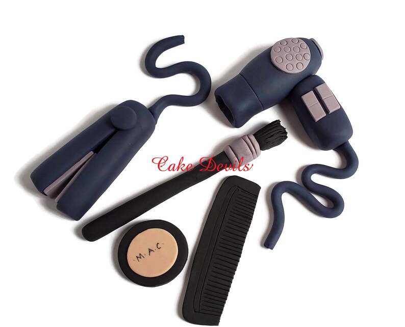 May include: A set of blue and black hair styling tools, including a hairdryer, curling iron, comb, and makeup brush. The makeup brush has a purple handle and the makeup compact has the text "M.A.C." on it.