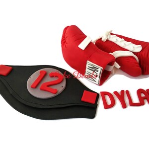 May include: Red boxing gloves with white laces and a black championship belt with the number 12 on it. The name Dylan is spelled out in red letters.